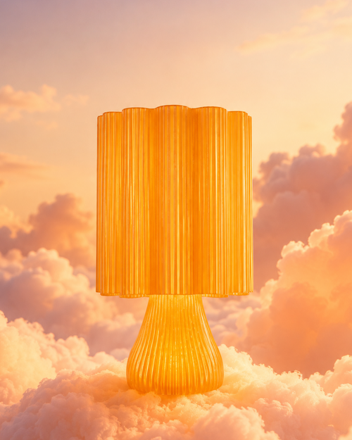 A glowing golden lamp with a pleated cylindrical shade and ribbed base, set against a dreamy sky filled with soft clouds in warm sunset tones.