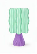 A modern sculptural table lamp with a wavy mint green shade and a ribbed purple base, shown against a plain white background.